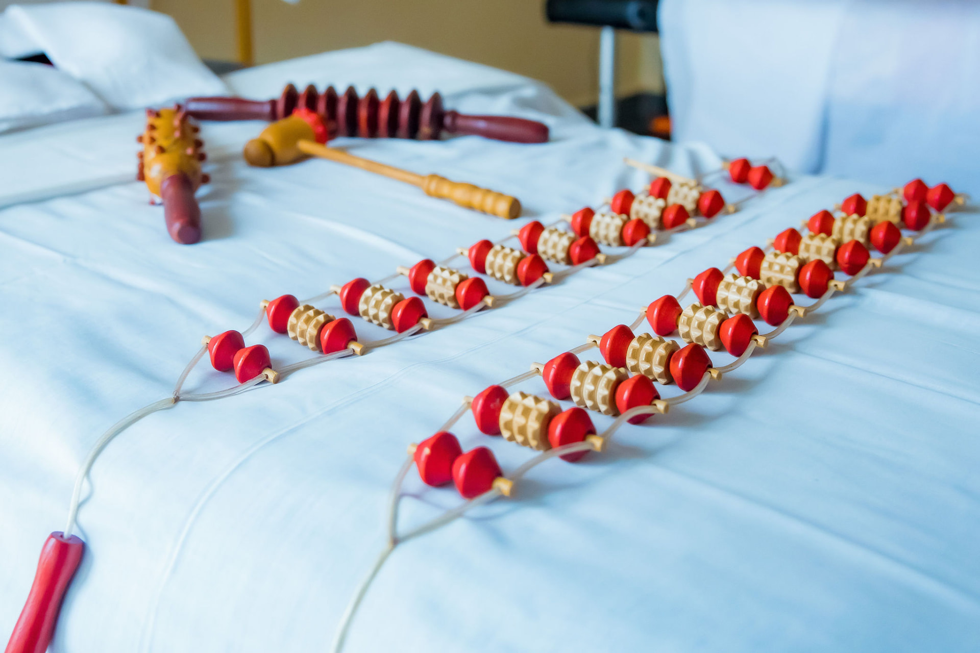 Wooden massage rollers and therapy tools laid out on a treatment bed
